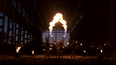 Professional-fire-show-in-the-old-hangar-of-the-aircraft-show-professional-circus-artists-three-women-in-leather-suits-and-a-man-with-two-flamethrowers..